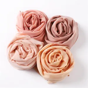 Detailaufnahme gerollter Chiffonschals in zarten Pastelltönen mit feiner Stoffstruktur.