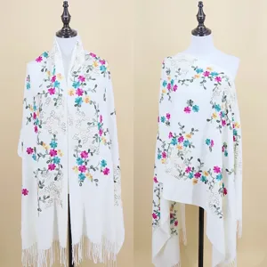 Detailed view of white imitation cashmere scarf with colorful floral embroidery and fringe trim.