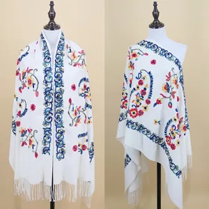 Detailed view of white cashmere-feel women shawl, featuring colorful paisley embroidery and fringe.