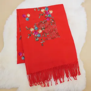 Detailed view of red winter cashmere-feel scarf with embroidered plum blossoms and tassels.