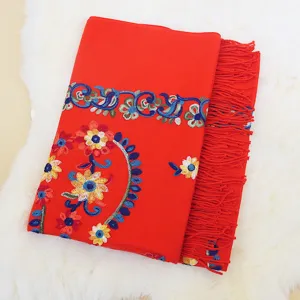 Detailed view of red ethnic floral embroidered cashmere feel winter scarf with fringe trim.