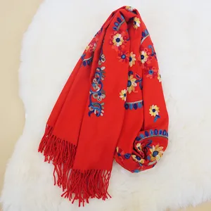 Detailed close-up of red cashmere-feel women winter scarf with ethnic embroidery and tassels.