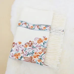 Detailed view of women's imitation cashmere embroidered floral shawl with fringe.