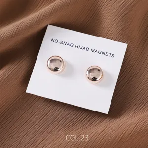Detail shot of round rose gold magnetic hijab pins on white display card with fabric.