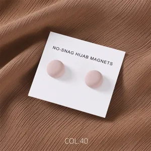 Close up of matte finish round magnetic hijab pins set in neutral brown fabric background.