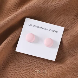 Close-up view of matte pink round magnetic hijab pins on backing card, detailed accessory shot.
