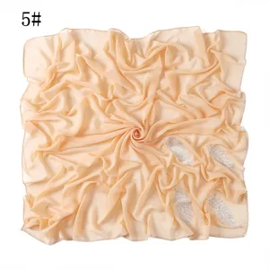 Details van lichtkaki chiffon vierkante hijab met mooie strass bladmotief en fijne vouwen.