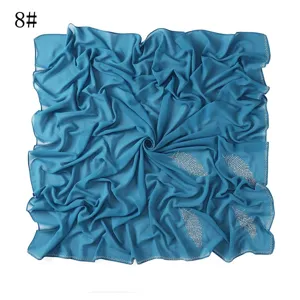 Gedetailleerd aanzicht van blauwe chiffon vierkante hoofddoek met strass bladmotief.