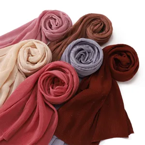 Primo piano dettagliato di diversi sciarpe in chiffon plissettato scintillante e colorato.