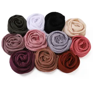 Primo piano dettagliato di sciarpe hijab in chiffon plissettato in vari colori vivaci.