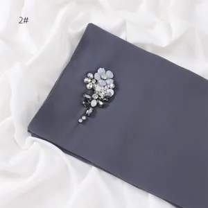 Detailed close-up of dark grey chiffon scarf with handmade crystal rhinestone flower embellishment.