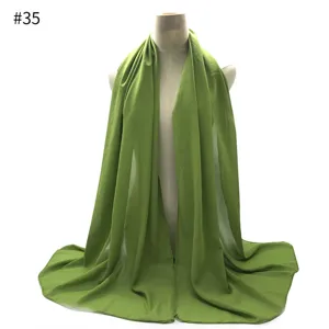 Green chiffon scarf detail view, elegant solid color hijab material close up for women.
