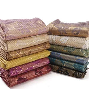 Pleated gold foil leaf pattern cotton linen scarf detail showing colorful stacked shawls