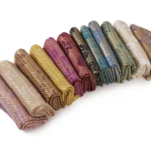 Detailed view of pleated metallic gold foil leaf printed cotton linen long scarf rolls.