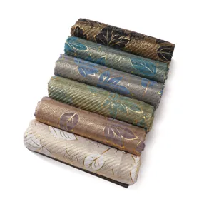 Detailed view of rolled linen cotton scarves with gold foil leaf patterns and stripes, varied.