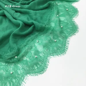 Detail van groene katoenen linnen sjaal met delicate kanten rand en prachtige ingelegde parels.