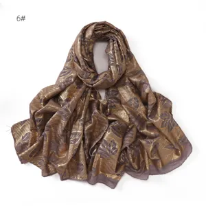 Detail view of metallic gold foil leaf printed pleated cotton linen scarf fabric texture.