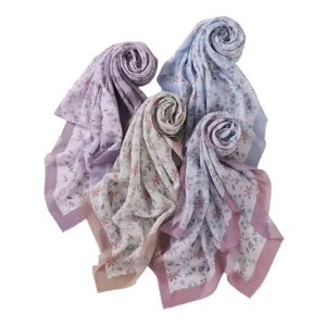 Detailed close-up view of pastel floral print square scarves featuring delicate wavy laser-cut edges.