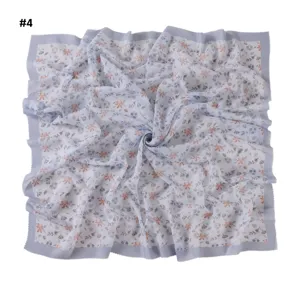 Close-up detail of floral square scarf with wave edge, soft fabric and elegant daisy print.