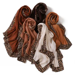Vue détaillée de longs foulards en lin plissé doux dotés de superbes bordures léopard.