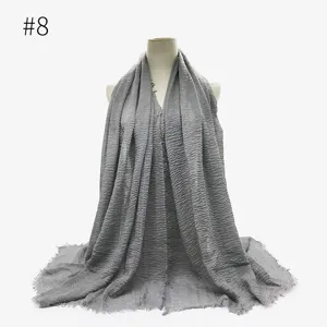 Dettaglio di sciarpa hijab stropicciata grigia, con consistenza morbida e bordi frangiati eleganti.