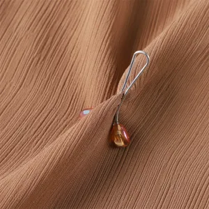 Close-up of a silver-toned metal U-shaped scarf clip with an amber crystal teardrop.
