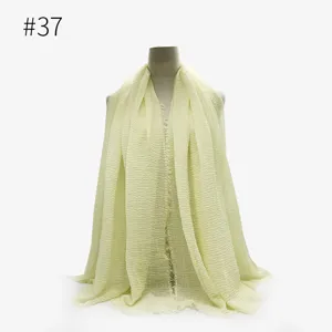 Dettaglio della sciarpa hijab stropicciata giallo chiaro con morbida trama e frange.