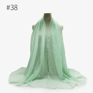 Dettaglio scialle hijab spiegazzato verde menta con tessitura morbida e bordi frangiati.