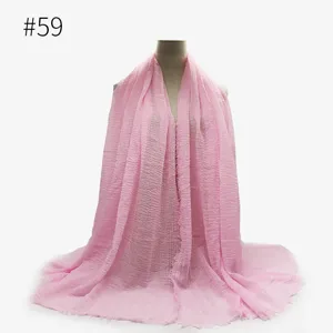 Dettaglio sciarpa stropicciata rosa, mostra consistenza morbida, bordi con frange e drappeggio.