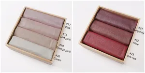 Detailed view of glitter metallic viscose fringe shawl showing various color choices in wooden box.