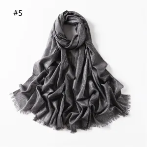 Close-up detail of grey shimmering viscose scarf with metallic threads and short fringe ends.