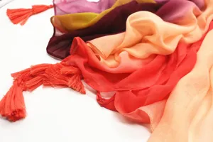 Detail view of soft gradient cotton scarf with colorful tassels, cozy fabric and artistic multi-color design.