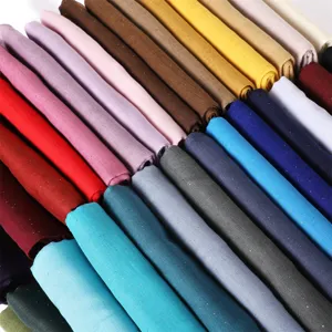 Close-up view of lightweight solid color glitter viscose scarves folded neatly in various vibrant shades.