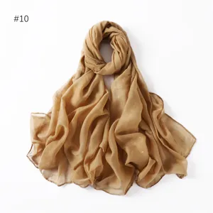 Shimmering gold glitter detail on lightweight sheer fabric, elegant textured wrap close-up.
