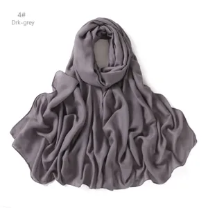 Gros plan détail écharpe modal gris foncé, tissu doux et respirant, accessorio léger.