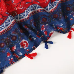 Close-up detail of bohemian style red and blue patchwork printed scarf with tassels.