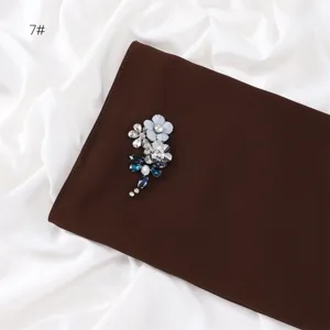 Rhinestone flower brooch detail, sparkling crystal embellishment on elegant brown fabric.