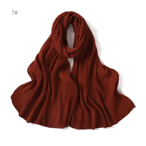 Primo piano dettagliato della sciarpa in chiffon plissettato e glitterato rosso ruggine morbido.