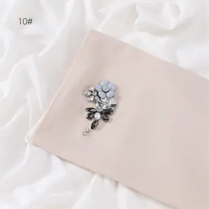 Close-up detail of handmade rhinestone flower brooch on elegant solid color chiffon hijab scarf.