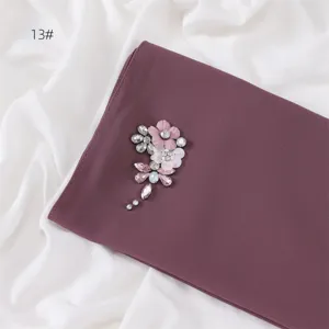 Detailed view of dark purple chiffon hijab scarf featuring sparkling crystal flower brooch design.