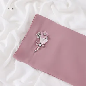 Close-up detail of the elegant chiffon scarf with sparkling rhinestones and floral patch.