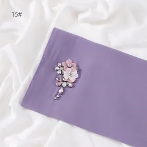 Detail of solid color purple chiffon scarf featuring handmade rhinestone flower brooch embellishment.