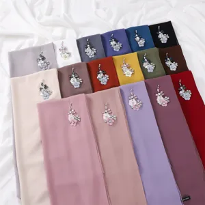 Detailed shot of multi-color chiffon hijabs decorated with crystal flower and dragonfly brooches.