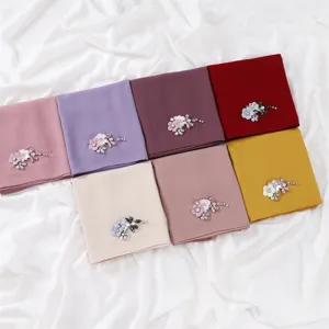 Detail view of solid chiffon scarves with handmade rhinestone flower and dragonfly decor.