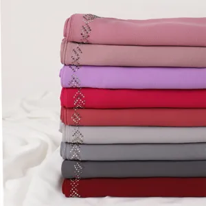 Detailed view of stacked chiffon hijab scarves featuring elegant rhinestone chain decorations.