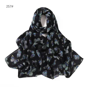 Dettaglio sciarpa lunga in chiffon con stampa a farfalla, tessuto nero e motivo floreale blu.