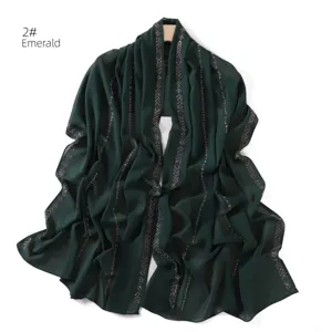 Close-up detail of emerald green chiffon scarf featuring shimmering rhinestone chain embellishments.