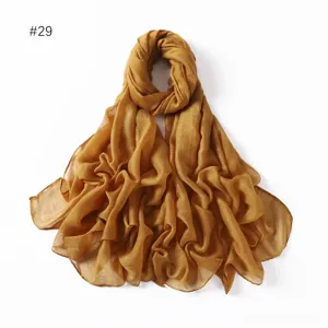 Detail view of shimmering metallic glitter viscose linen scarf in solid caramel gold color.