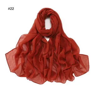Detailed view of rust orange rhinestone embellished sheer long scarf, elegant fabric texture.