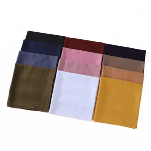 Vista detallada de pañuelos cuadrados de algodón liso multicolor, tela suave y plegado ordenado.